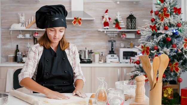 Ritratto di bambini che mettono l'ingrediente della farina sull'impasto di pan di zenzero fatto in casa