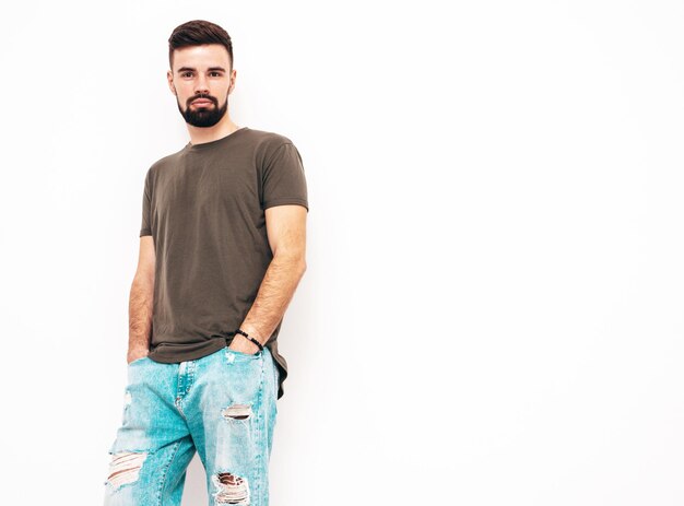 Ritratto di bel modello lambersexual hipster elegante e sicuro di sé vestito con maglietta e jeans Moda maschile isolato su parete bianca in studio