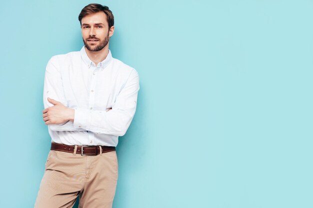 Ritratto di bel modello sorridente Uomo alla moda sexy vestito in camicia e pantaloni Moda uomo hipster in posa vicino al muro blu in studio isolato