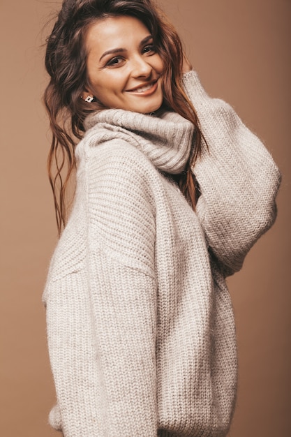 Ritratto di bella dolce carina donna bruna sorridente. Ragazza in maglione casual grigio. Modello in posa in studio