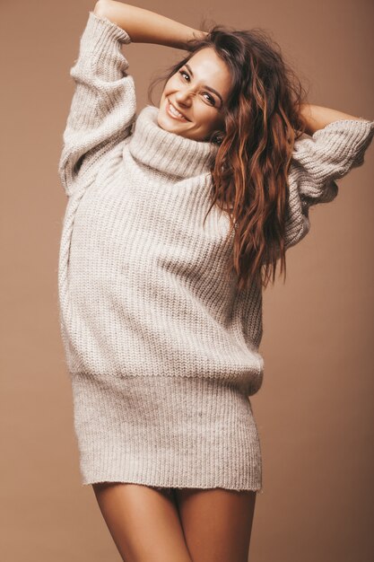 Ritratto di bella dolce carina donna bruna sorridente. Ragazza in maglione casual grigio. Modello in posa in studio