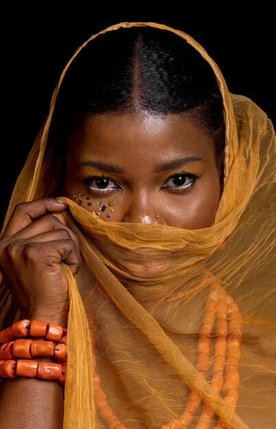 Ritratto di bella donna africana che indossa accessori tradizionali e velo giallo