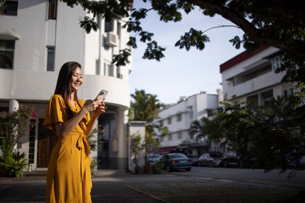 Ritratto di bella donna asiatica che utilizza smartphone all'aperto in città