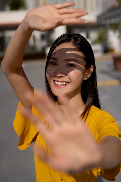 Ritratto di bella donna asiatica in vestito giallo che posa all'aperto nella città