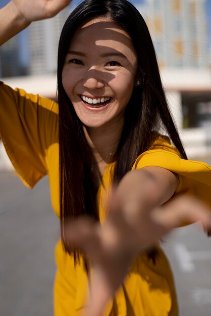 Ritratto di bella donna asiatica in vestito giallo che posa all'aperto nella città