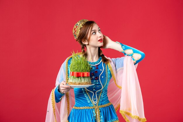 Ritratto di bella donna azera in abito tradizionale con semeni su rosso