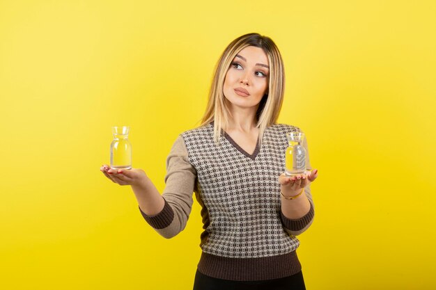 Ritratto di bella donna bionda che tiene due bicchieri di acqua naturale.