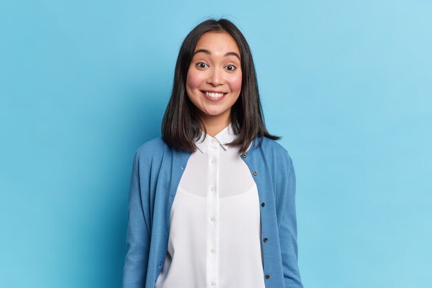 Ritratto di bella donna bruna sorride a trentadue denti sente qualcosa di piacevole indossa casual modelli di maglia e camicia indoor