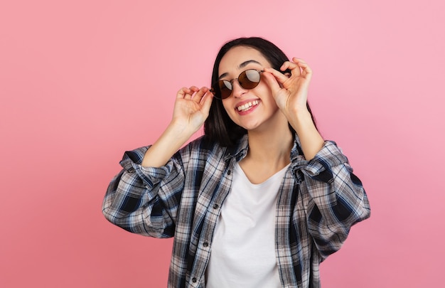 . Ritratto di bella donna caucasica sulla parete rosa corallo con copyspace. Modello alla moda. Concetto di emozioni umane, espressione facciale, vendite, pubblicità, moda, gioventù.