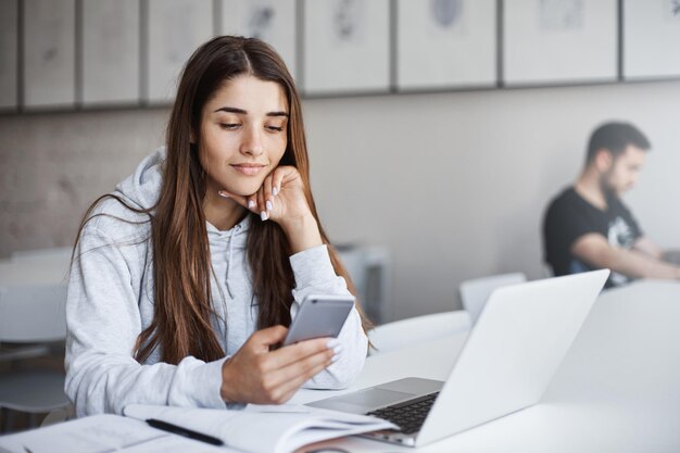 Ritratto di bella donna che usa il cellulare per sfogliare il suo profilo sui social media e scorrere le foto