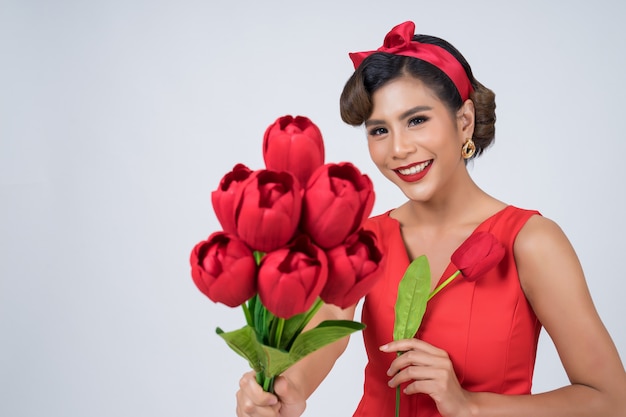 Ritratto di bella donna con bouquet di fiori di tulipano rosso