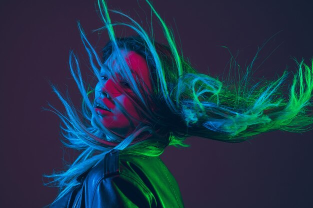 Ritratto di bella donna con i capelli che soffia in luce al neon colorato