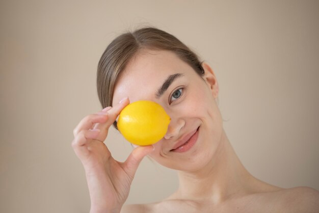 Ritratto di bella donna con la pelle chiara che tiene il frutto del limone