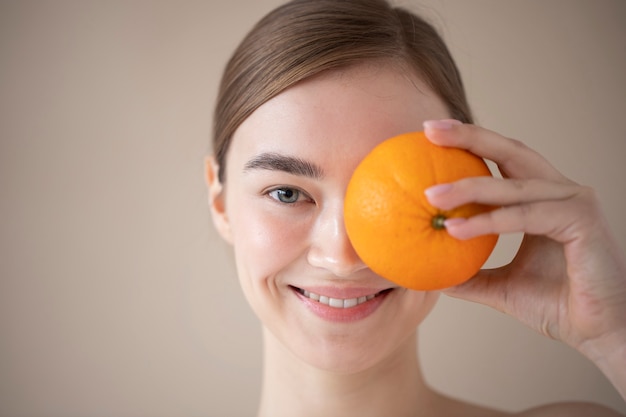 Ritratto di bella donna con pelle chiara che tiene frutta arancione