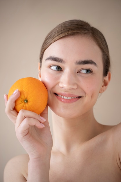 Ritratto di bella donna con pelle chiara che tiene frutta arancione