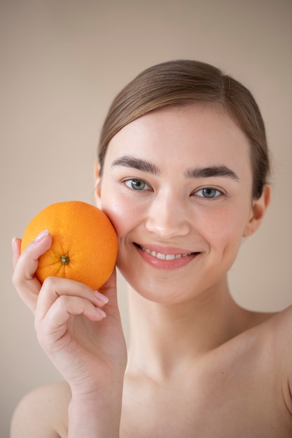 Ritratto di bella donna con pelle chiara che tiene frutta arancione