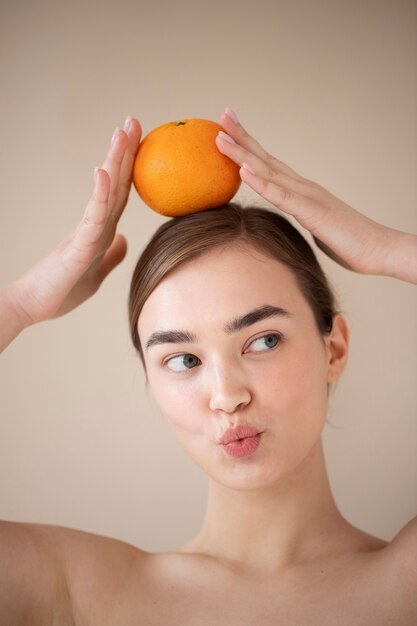Ritratto di bella donna con pelle chiara che tiene frutta arancione