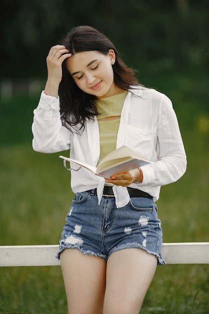 Ritratto di bella donna. La donna ha letto un libro. Signora in una camicia bianca.