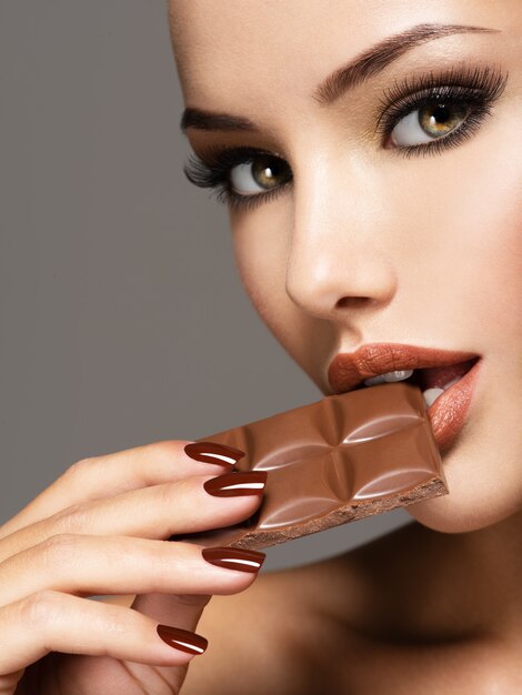 Ritratto di bella donna mangia il cioccolato dolce con gioia