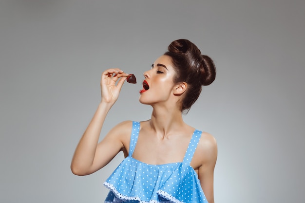 Ritratto di bella donna pin-up che mangia fragola in cioccolato