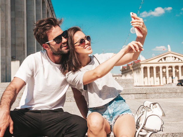 Ritratto di bella donna sorridente e del suo bel ragazzo Donna in abiti estivi casual Famiglia allegra felice Femmina che si diverte Coppia in posa per strada con occhiali da sole Scattare foto selfie