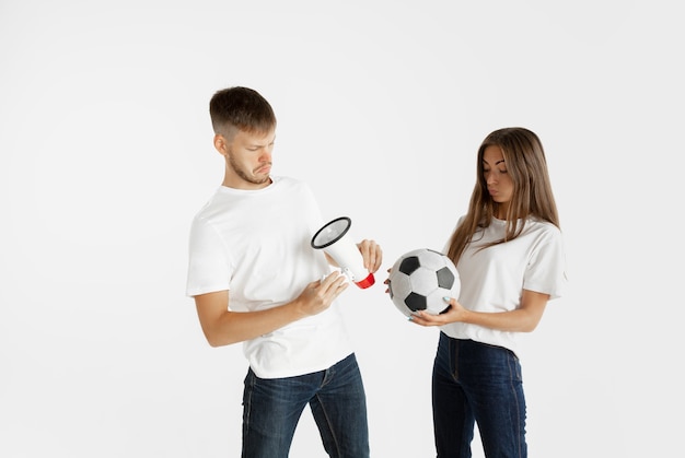 Ritratto di bella giovane coppia di tifosi di calcio o di calcio su sfondo bianco studio. Espressione facciale, emozioni umane, pubblicità, concetto di sport. Donna e uomo che salta, urla, si diverte.