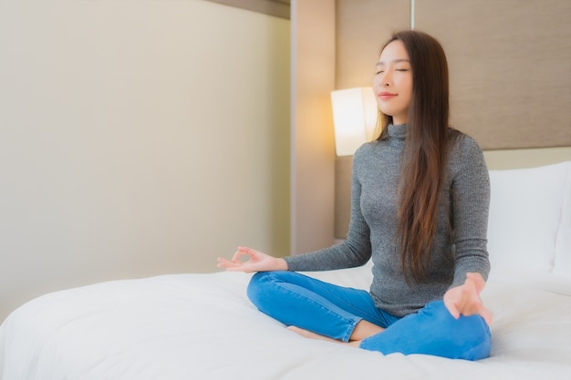 Ritratto di bella giovane donna asiatica che fa meditazione sul letto