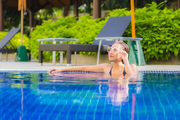 Ritratto di bella giovane donna asiatica che si rilassa intorno alla piscina all'aperto nella località di soggiorno dell'hotel