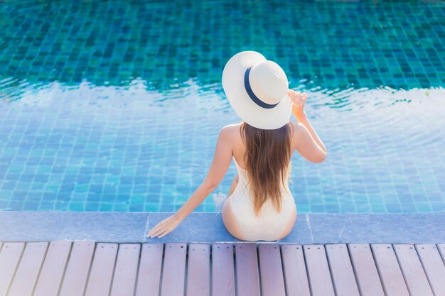 Ritratto di bella giovane donna asiatica che si rilassa intorno alla piscina all'aperto nella località di soggiorno dell'hotel
