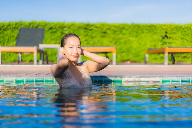 Ritratto di bella giovane donna asiatica che si rilassa intorno alla piscina all'aperto nella località di soggiorno dell'hotel