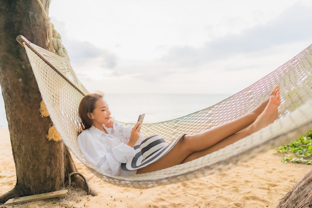 Ritratto di bella giovane donna asiatica che si rilassa sull'amaca intorno alla spiaggia in vacanza