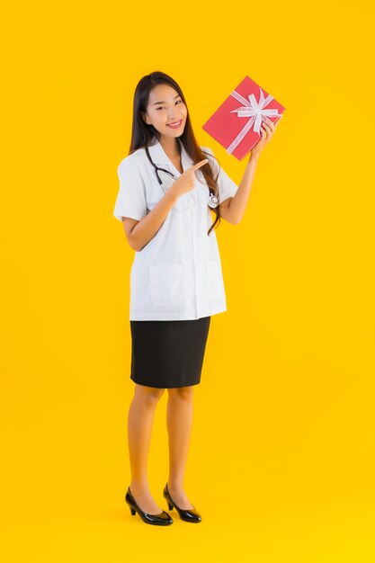 Ritratto di bella giovane donna asiatica del medico che mostra il contenitore di regalo rosso