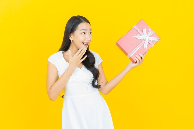Ritratto di bella giovane donna asiatica sorriso con confezione regalo rossa
