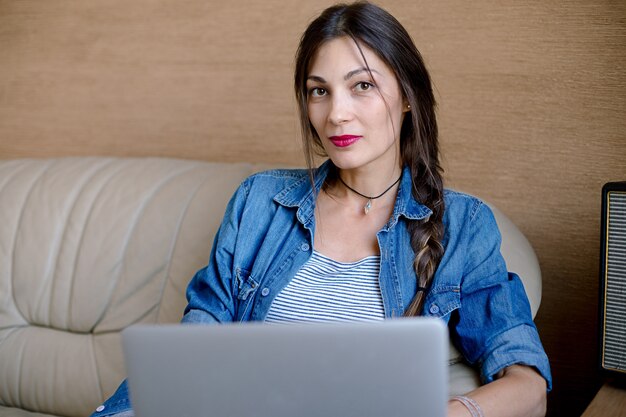 Ritratto di bella giovane donna sorridente che per mezzo del computer portatile