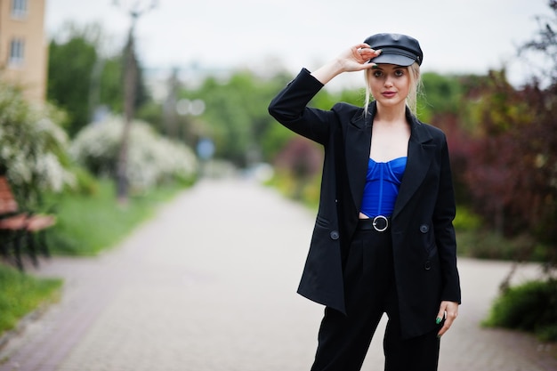Ritratto di bella modella bionda donna moda sexy in berretto e in tutto il corsetto blu nero con trucco luminoso