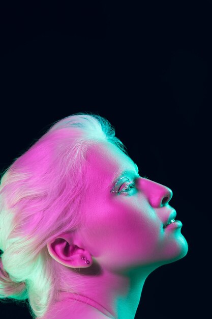 Ritratto di bella ragazza albina isolata su studio scuro in luce al neon