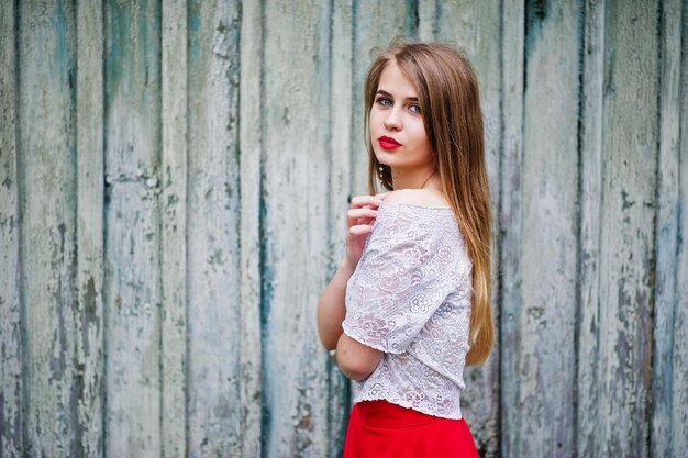 Ritratto di bella ragazza con labbra rosse su sfondo di legno usura su abito rosso e camicetta bianca