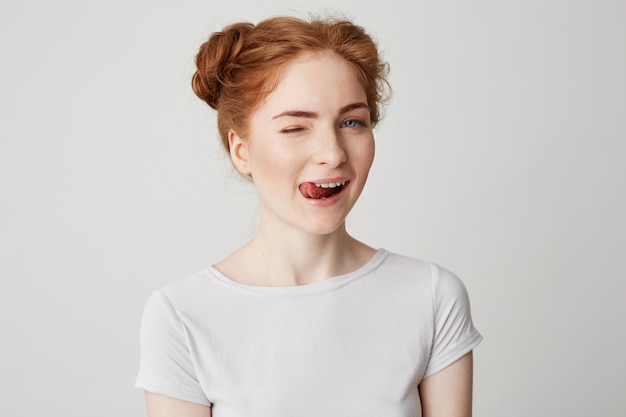 Ritratto di bella ragazza di redhead che sorride mostrando sbattere le palpebre della lingua.
