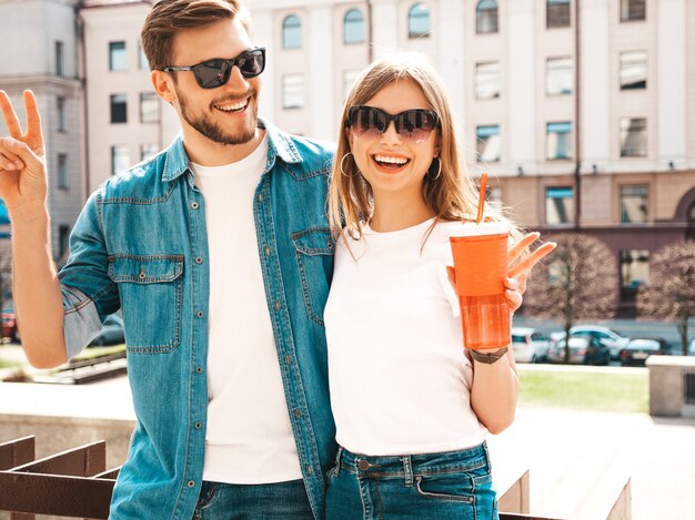 Ritratto di bella ragazza sorridente e il suo bel ragazzo in abiti estivi casual. . Donna con bottiglia di acqua e paglia