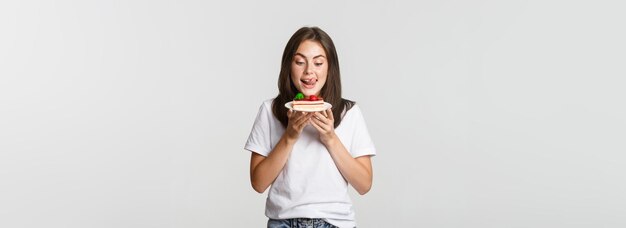 Ritratto di bella ragazza tentata che lecca le labbra come guardando la torta