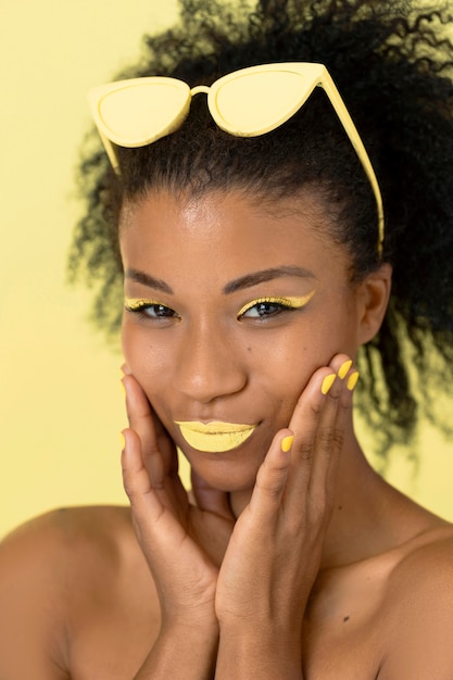 Ritratto di bellezza della donna afro con lucidalabbra giallo e occhiali da sole