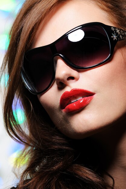 Ritratto di bello fronte femminile grazioso con occhiali da sole moda glamour su di esso