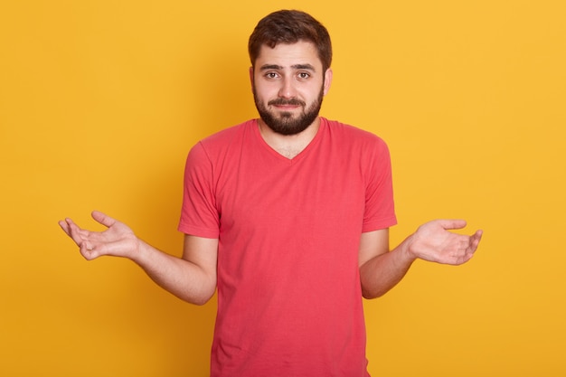 Ritratto di bello giovane uomo barbuto caucasico con capelli scuri, maschio bello che guarda direttamente la macchina fotografica con emozione confusa