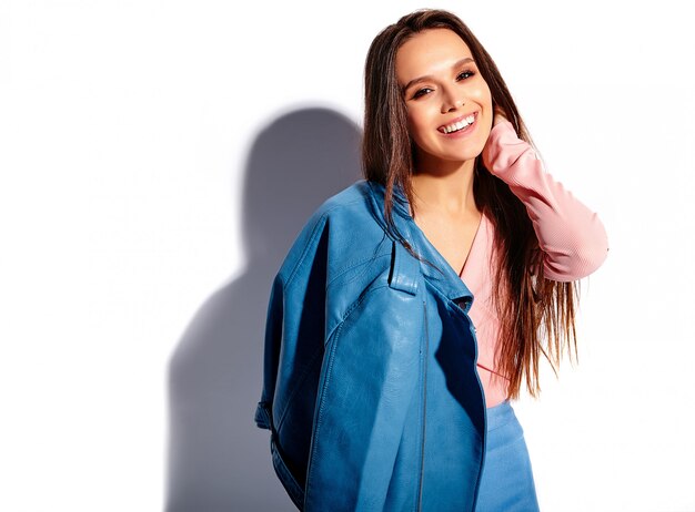 Ritratto di bello modello caucasico sorridente della donna del brunette in vestiti alla moda di estate dentellare e blu luminosi isolati su priorità bassa bianca