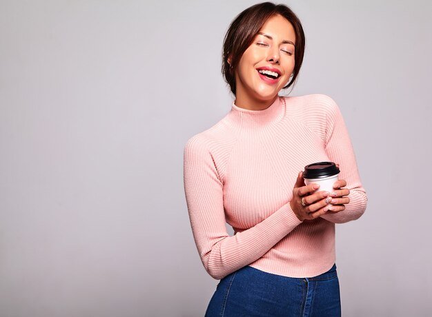 Ritratto di bello modello sveglio della donna del brunette in vestiti casuali di colore rosa di estate senza trucco isolato su bianco