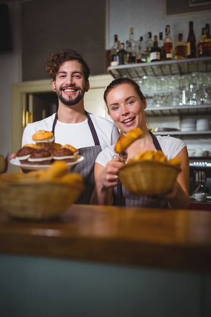 Ritratto di cameriere e il cameriere tenendo cupcakes e pane