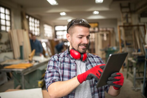 Ritratto di casual carpentiere operaio di mezza età con tablet nel laboratorio di falegnameria