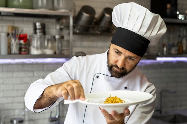 Ritratto di chef maschio in cucina che tiene piatto di cibo