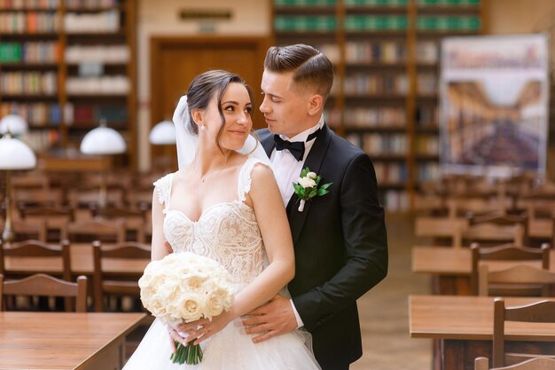 Ritratto di coppia di innamorati della sposa che si guardano in biblioteca