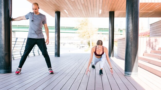 Ritratto di coppia sportiva facendo esercizi di stretching nel parco prima dell&#39;allenamento